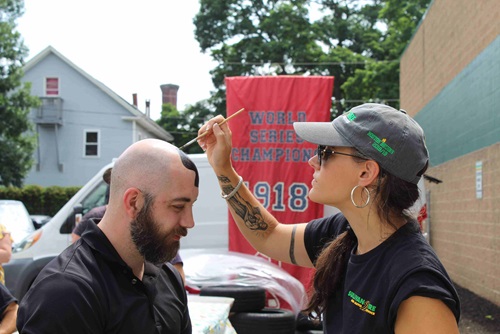 A Sullivan Tire employee getting their shaved head painted with the Sullivan Tire "S" logo.