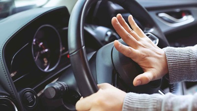 A hand pressing on the vehicle's horn